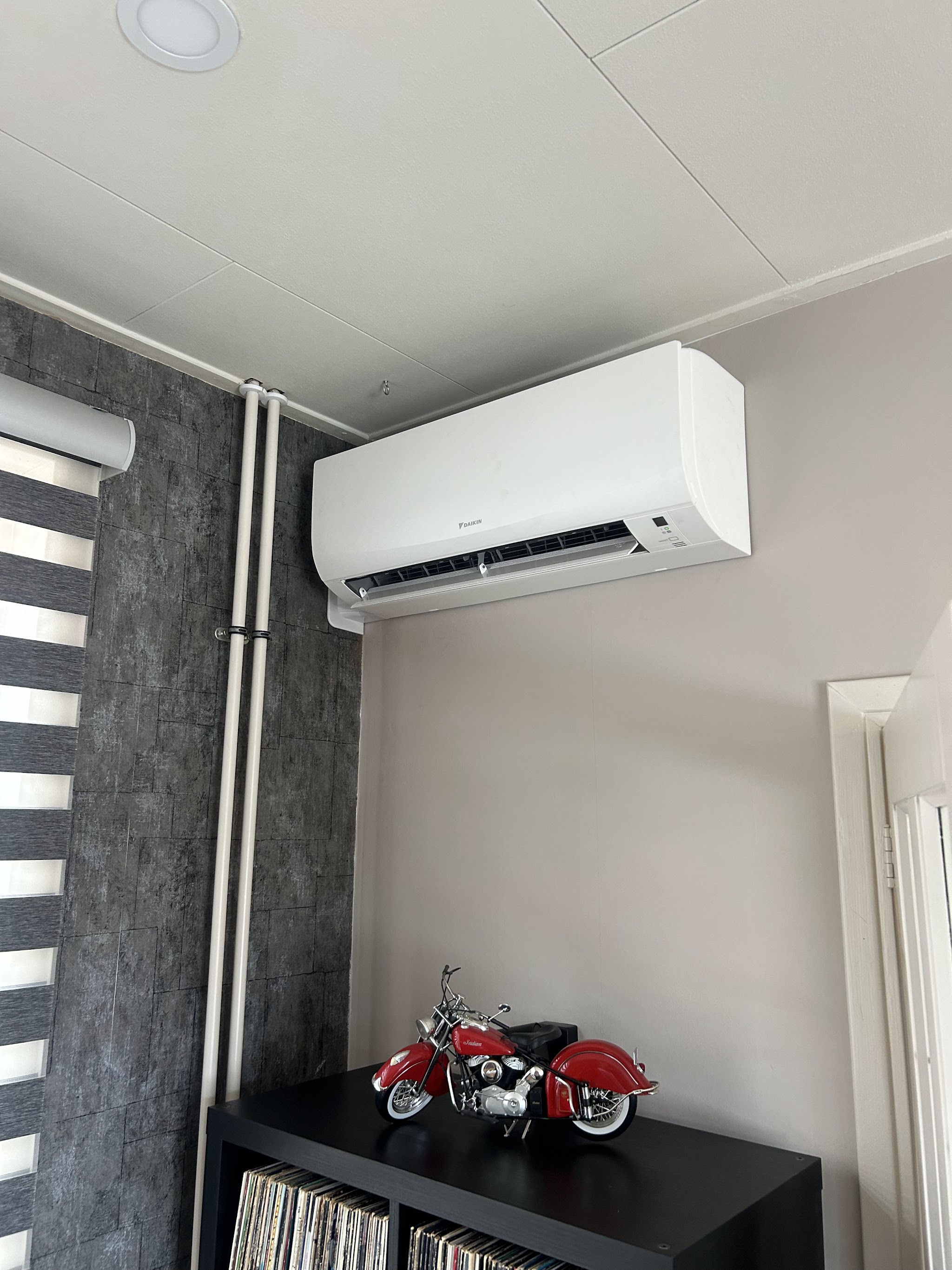 Airco-binnenunit aan de wand, leidingen weggewerkt in een witte goot